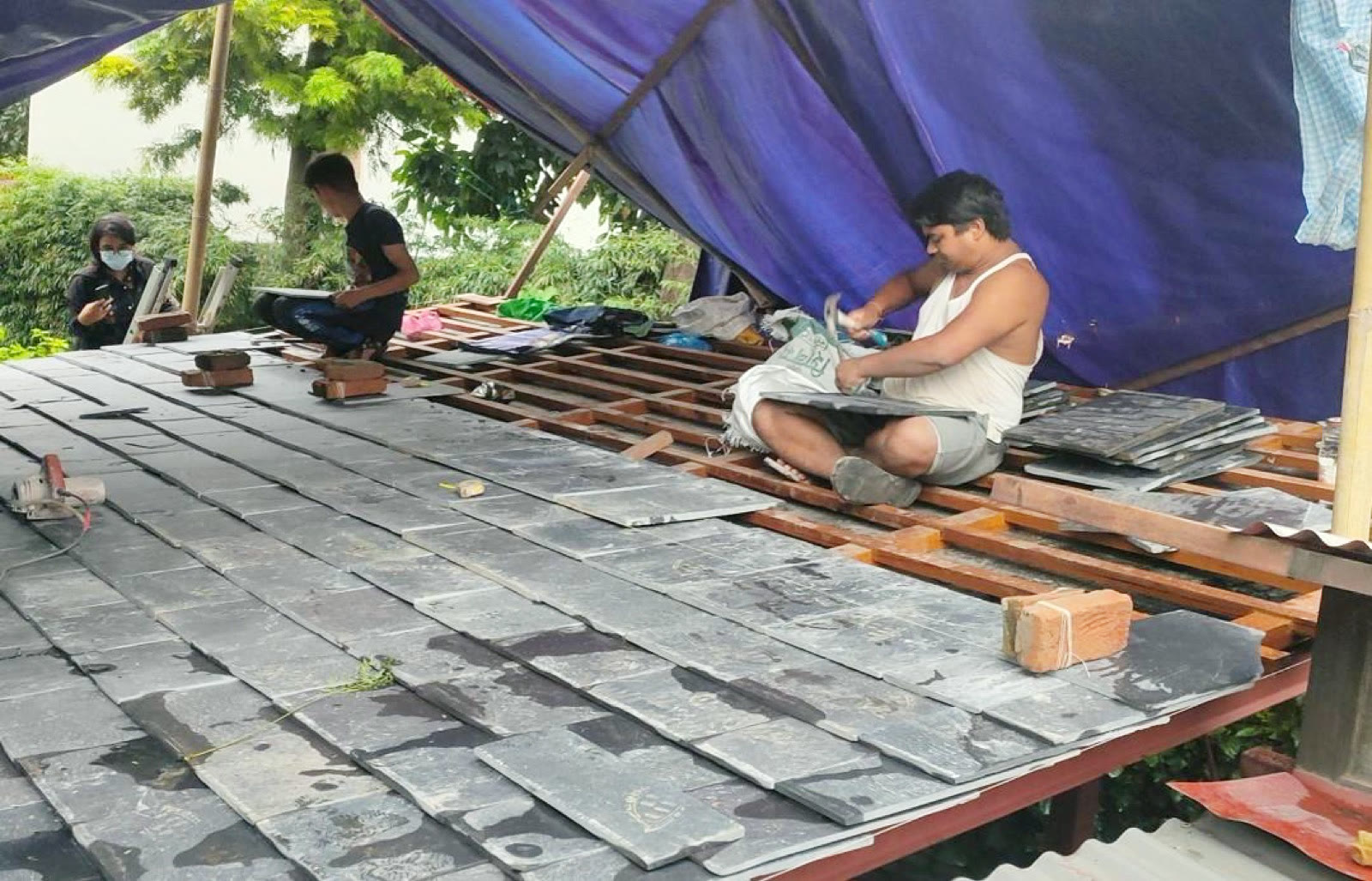 工人以手工一片片鋪設石板瓦屋頂