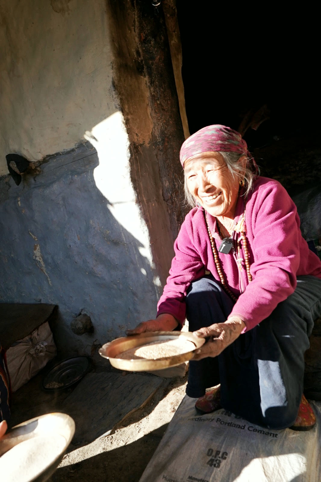 一位村中婦人在屋內篩穀，光從高處落下